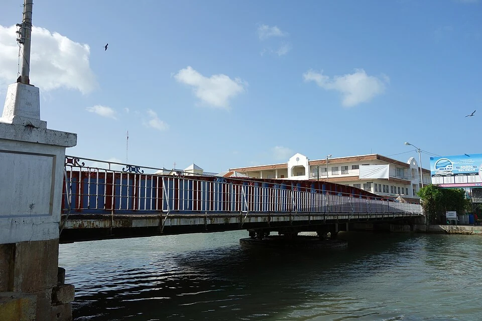 The Swing Bridge over Haulover Creek in Belize City, photographed from the water, with buildings along the far bank.