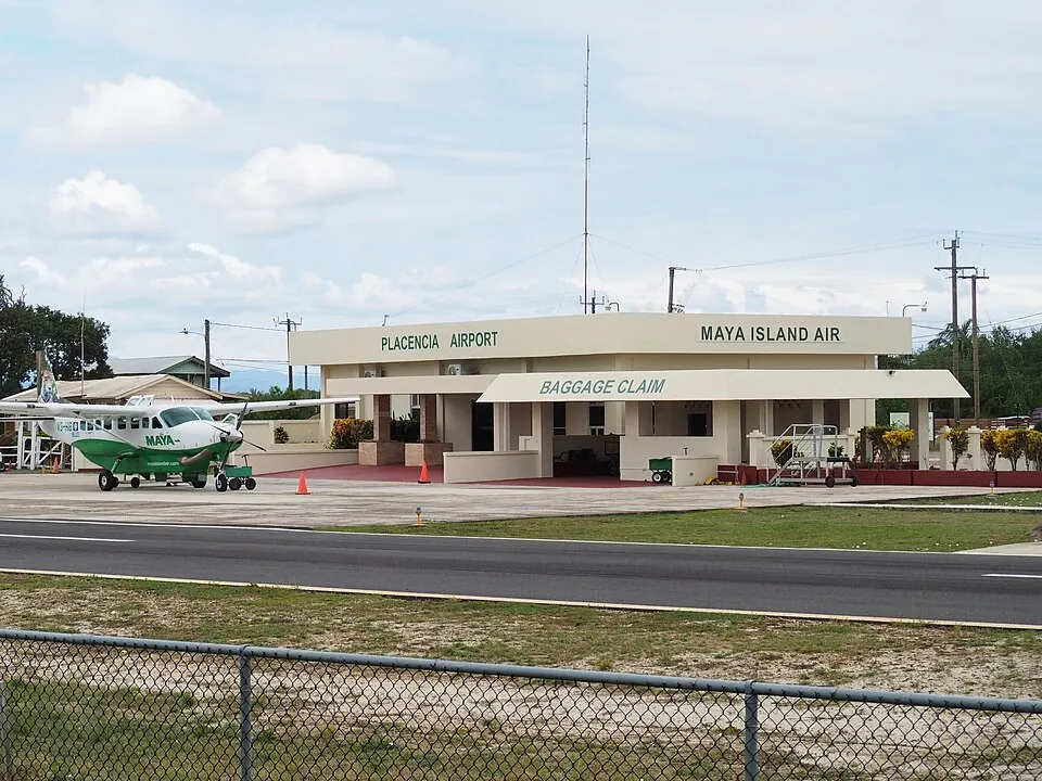 The single-storey terminal building at Placencia airstrip, with a Maya Island Air Cessna Caravan parked on the apron beside it.